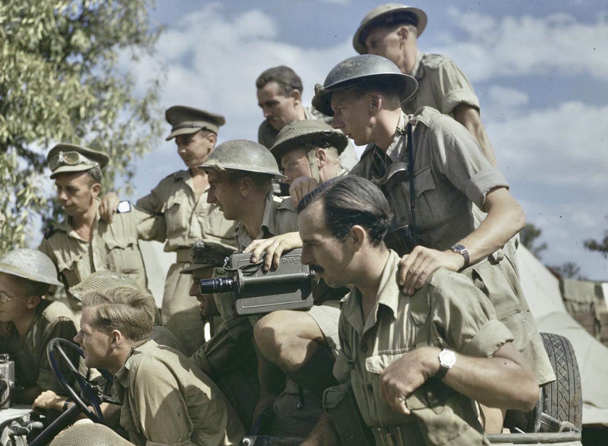 Men of the AFPU in the field receiving last minute instructions from the Unit Adjutant. A De Vry camera is on the knee of a cameraman in the centre.